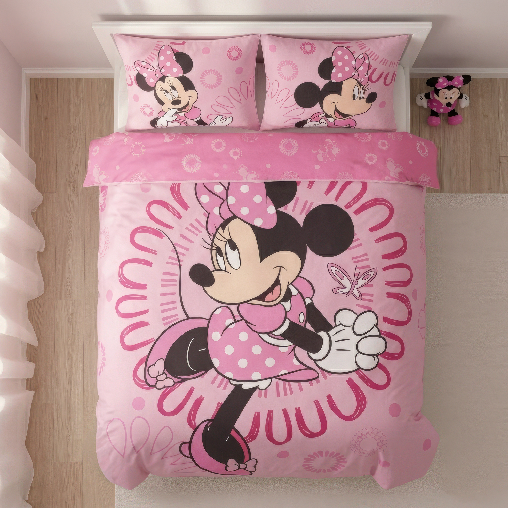 Draufsicht der Minnie-Mouse-Kinderbettwäsche auf einem hellen Holzboden; der rosa Deckenbezug präsentiert eine große Minnie Maus in einem Kreis- und Schmetterlings-Design, ergänzt durch zwei passende Kopfkissen am oberen Ende.
