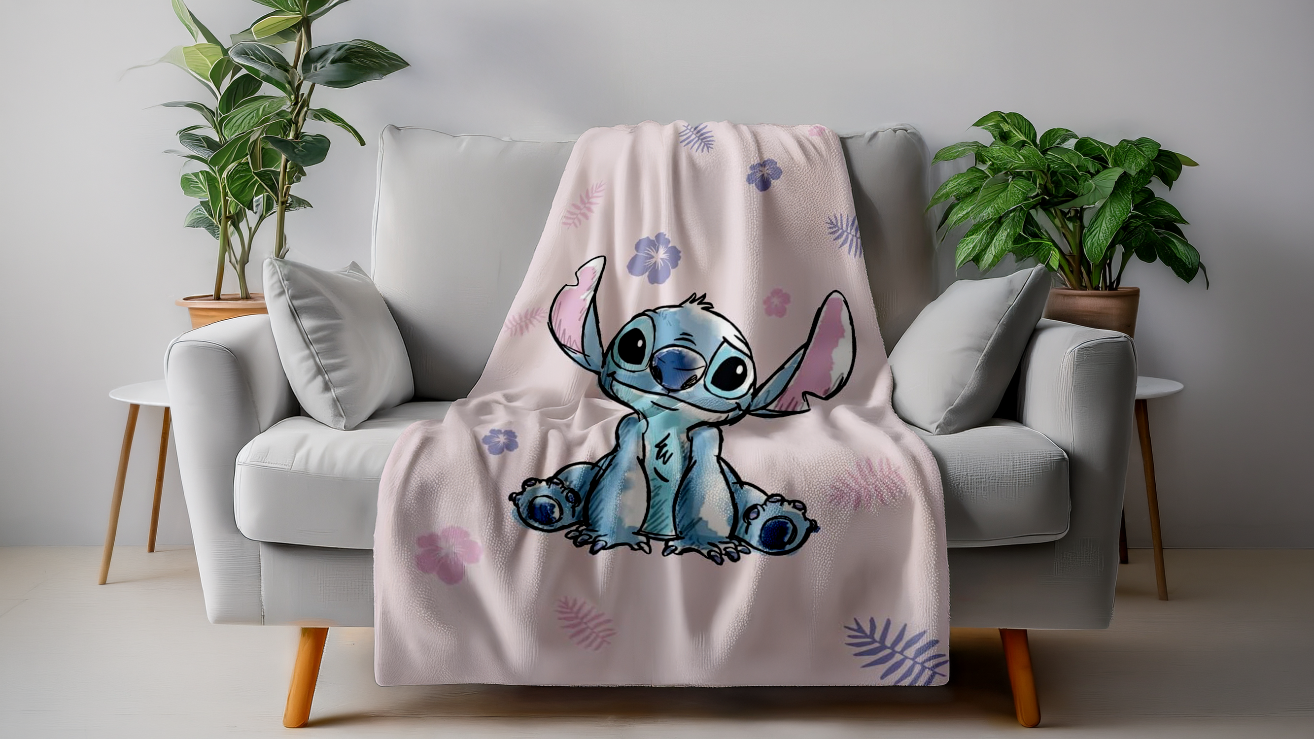 Rosa Disney Stitch Kuscheldecke mit Blumen- und Blattmuster auf grauem Sofa – weiche Lizenz-Wohndecke für Kinder und Erwachsene