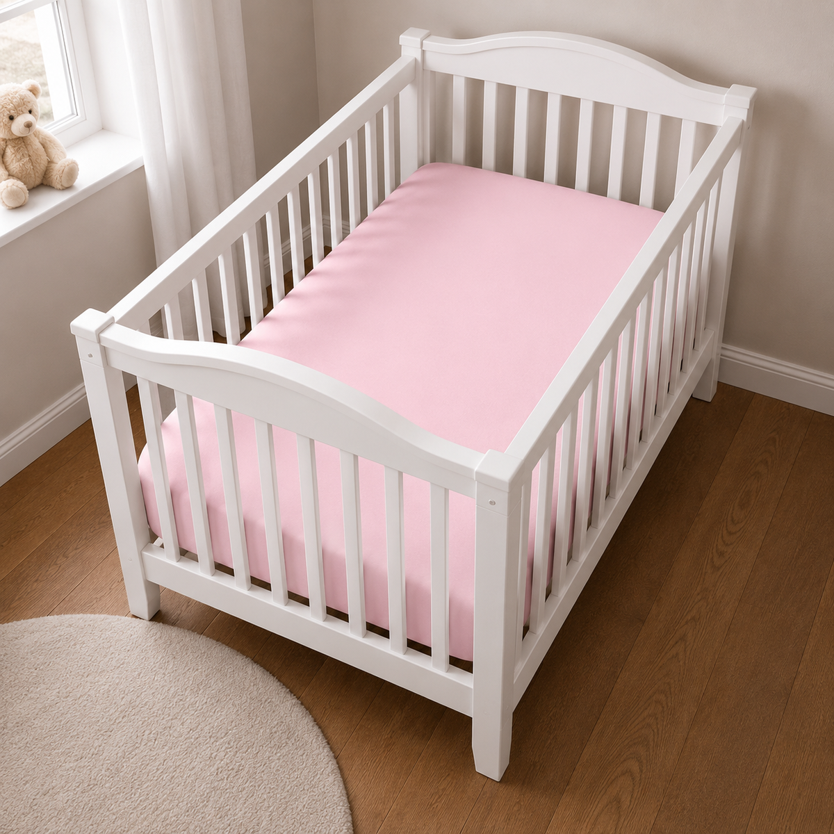 2er Set Baby Jersey Spannbetttuch 60x120 cm - 70x140 cm Rosa Baumwolle aus einer schrägen Perspektive in einem Babybett dargestellt