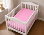 2er Set Baby Jersey Spannbetttuch 60x120 cm - 70x140 cm Blütenrosa Baumwolle aus einer schrägen Perspektive in einem Babybett dargestellt