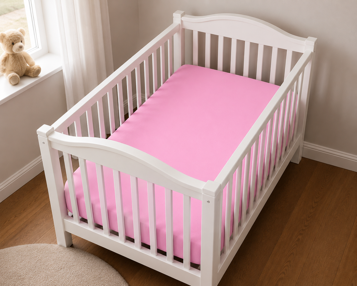 2er Set Baby Jersey Spannbetttuch 60x120 cm - 70x140 cm Blütenrosa Baumwolle aus einer schrägen Perspektive in einem Babybett dargestellt