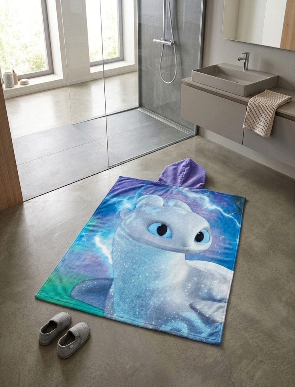 Rückseite von Dragons Badeponcho mit Kapuze 50x115 cm, 100% Baumwolle liegt auf einem Badezimmerboden.
