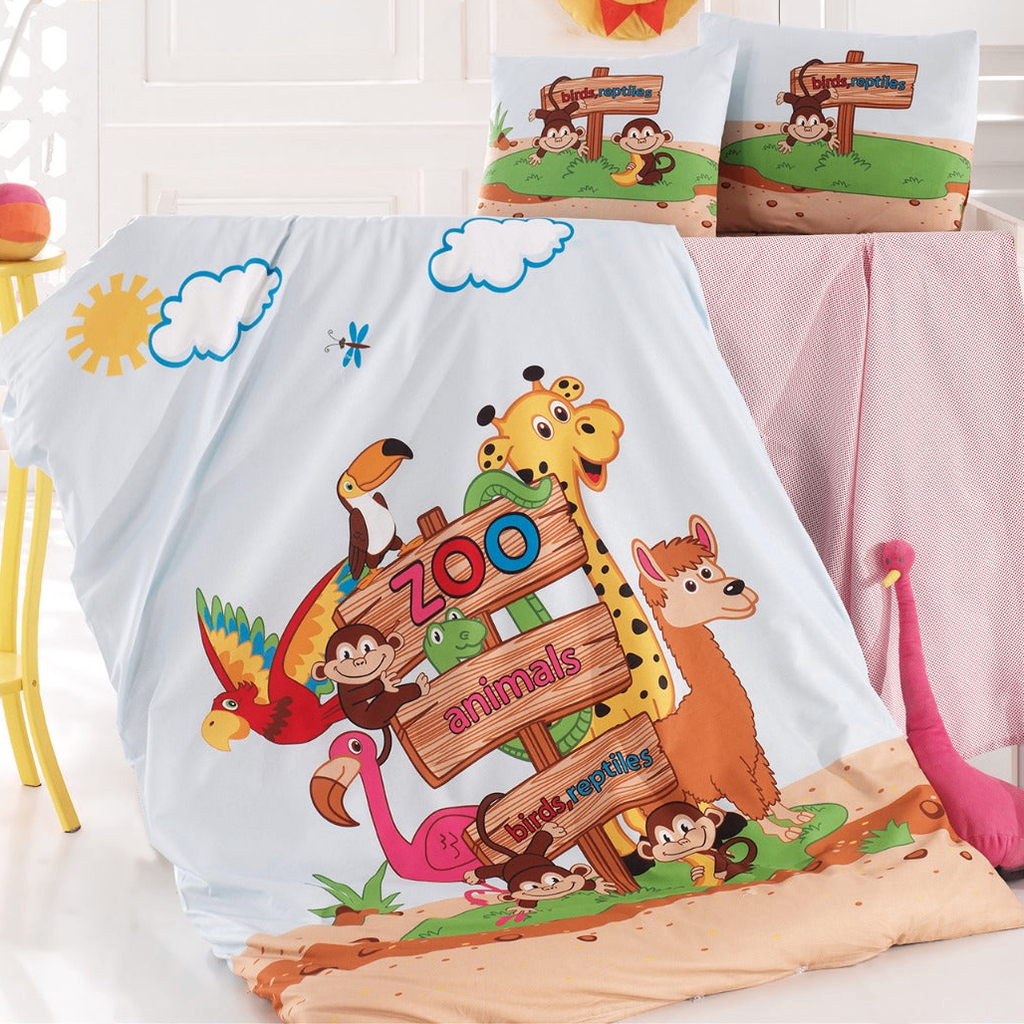 Eine bunte Zoo-Animals-Babybettwäsche, bestehend aus Kissen und Decke mit Illustrationen von Zootieren wie Giraffe, Affe, Flamingo und Papagei vor einem hellblauen Himmel mit Wolken und Sonne.
