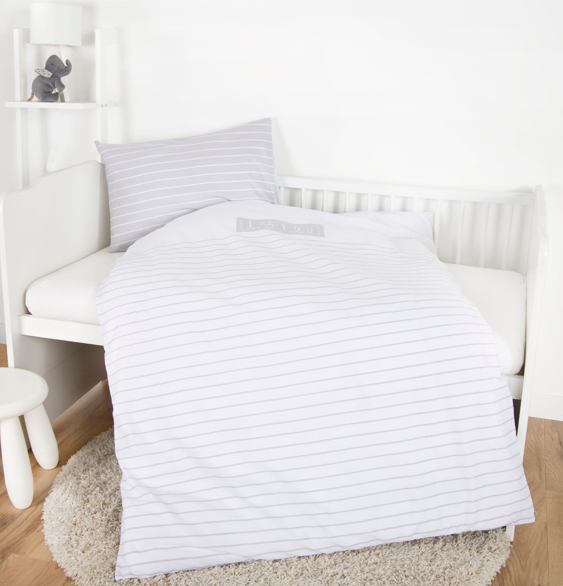 Herding I Love You Baby Bio-Bettwäsche 2 tlg 100 x 135 cm Baumwolle liegt auf einem Babybett. Grau-weißes Design mit "I love you" Schriftzug.