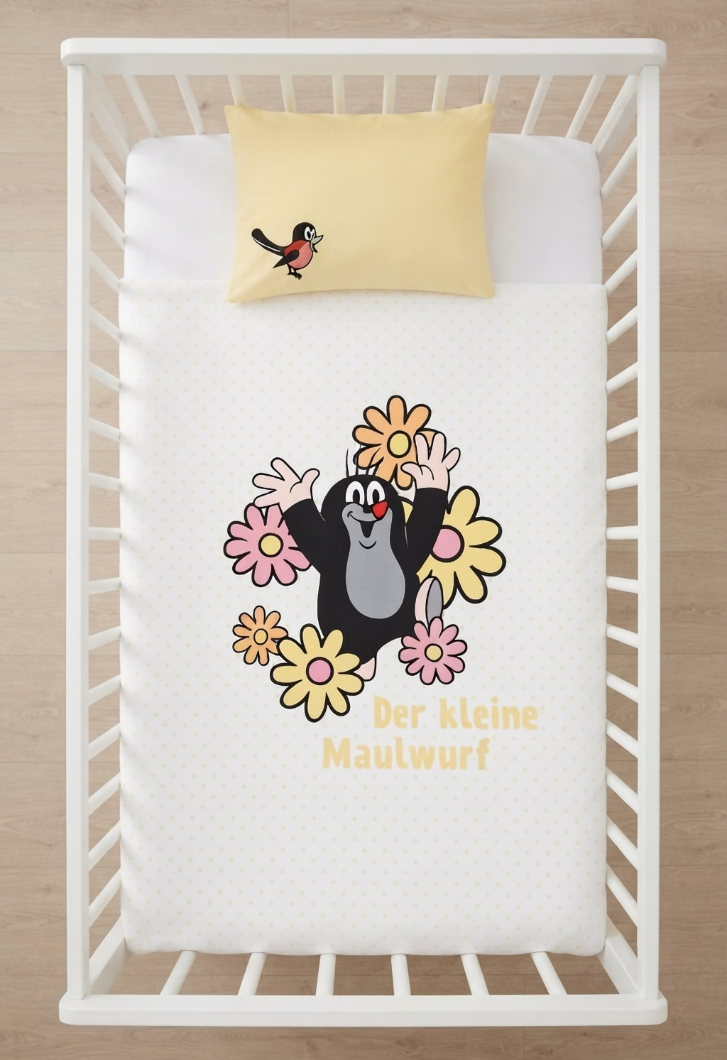 Herding Der kleine Maulwurf Baby Bettwäsche Set 100 x 135 cm Baumwolle in gelb-weiß wird aufgezogen in einem Babybett dargestellt.