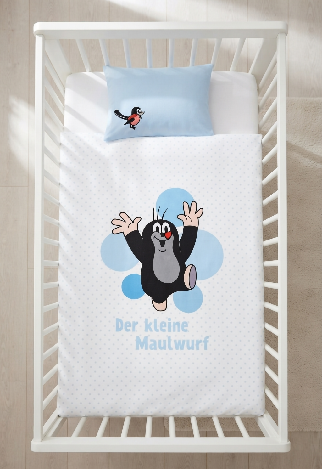 Herding Der kleine Maulwurf Baby Bettwäsche Set 100 x 135 cm Baumwolle in blau-weiß wird aufgezogen in einem Babybett dargestellt.