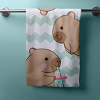 Produktbild des Capybara Badetuchs in der Frontalansicht. Drei gezeichnete, freundliche Capybaras im Comic-Stil trinken bunten Bubble Tea mit Strohhalm vor einem dekorativen, mintgrünen Zickzack-Muster.