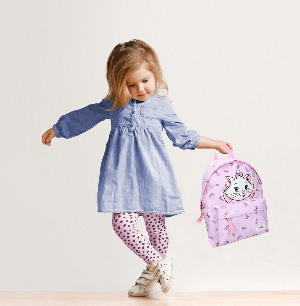 Frontansicht eines Kindes mit rosa Katzen‑Rucksack, hellem Outfit und neutralem Hintergrund. Der Rucksack zeigt ein Katzenmotiv und kleine Schleifen.