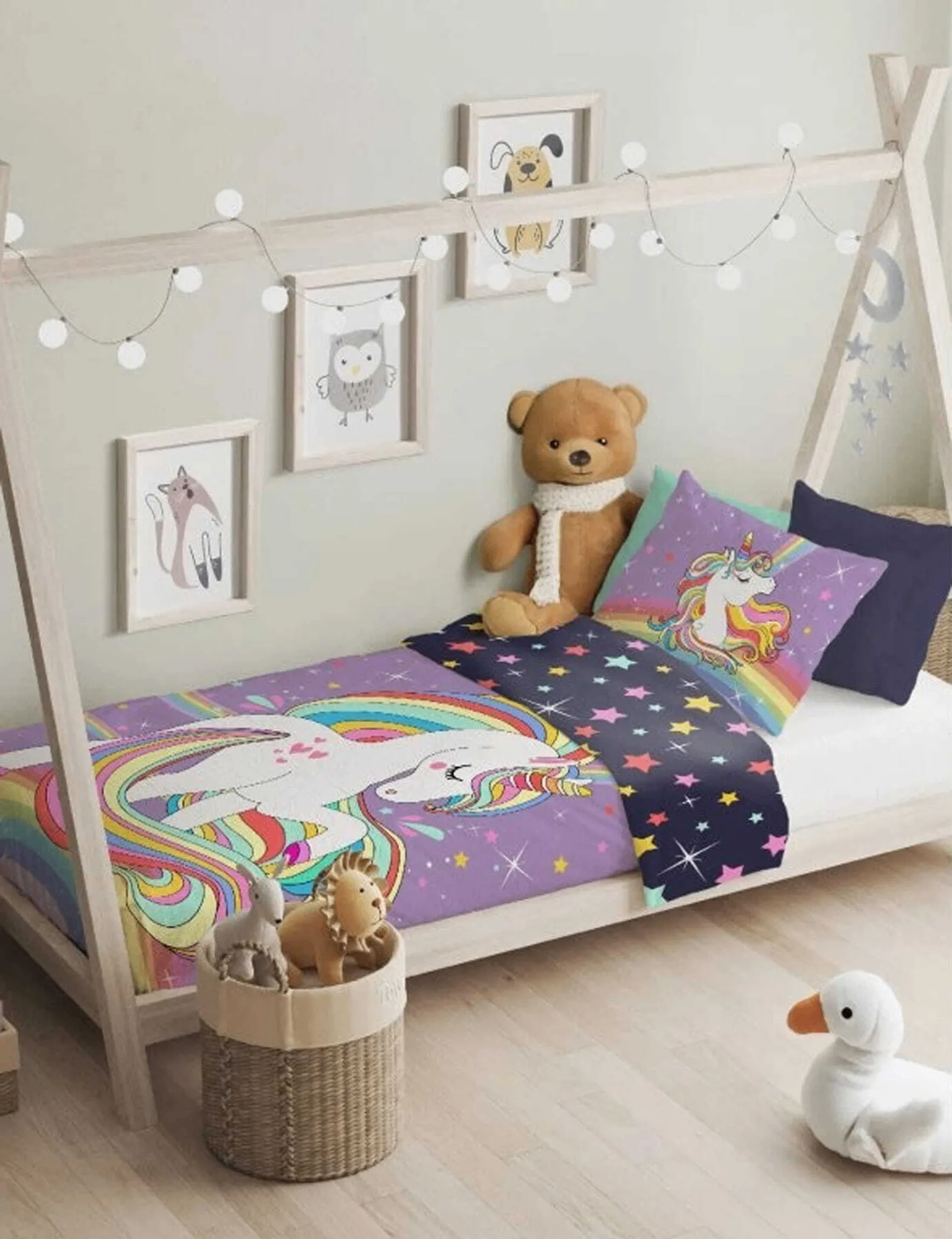 Tipi‑Holzbett mit bunter Unicorn‑Bettwäsche, großem Teddy, Wandbildern und Spielzeugkorb. Helles, freundliches Kinderzimmer.