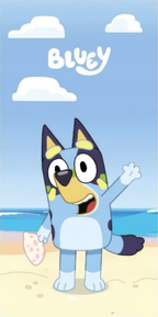 Frontansicht eines Bluey‑Motivs am Strand, winkend, mit pinkem Objekt. Heller Himmel, Wolken, klare Farben und freundliche Szene.