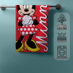 Minnie‑Handtuch am Stab, roter Hintergrund, Minnie im Punktkleid. Rechts Icons zu Baumwolle, Saugfähigkeit und Pflegeleichtigkeit.