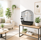 Vogelkäfig "Elizabeth" auf Holztisch im modernen Wohnzimmer, schwarze Gitter, weiße Basis, Holzstangen. Sofa, Pflanzen und Deko im Hintergrund.