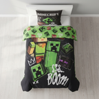 Bett mit Minecraft‑Bettwäsche, Creeper‑Motiven, TNT‑Blöcken und „SSS… BOOM“-Text. Helles Zimmer mit weißem Kopfteil und Holzfußboden.