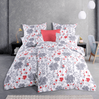 Bett mit weißer Blumen‑Bettwäsche in Grau und Rot. Modernes Zimmer mit grauer Wand, Hängelampen, Nachttisch und Deko‑Kissen.