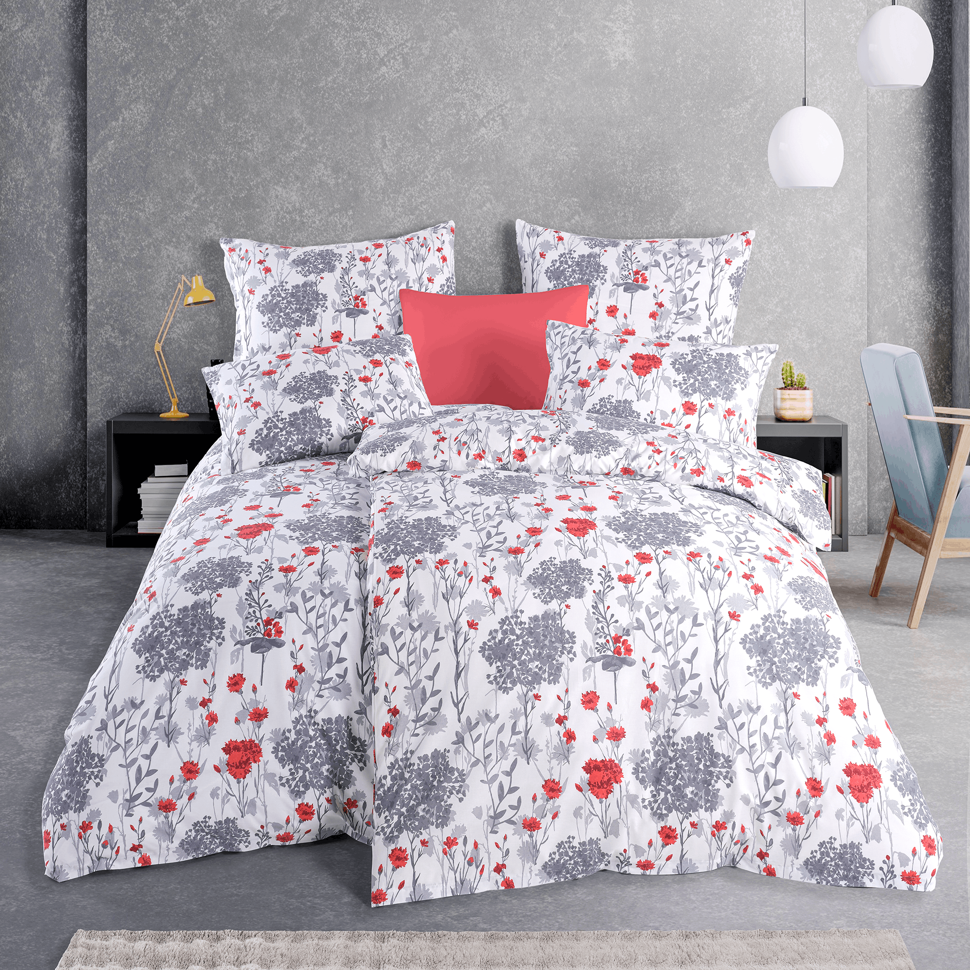 Bett mit weißer Blumen‑Bettwäsche in Grau und Rot. Modernes Zimmer mit grauer Wand, Hängelampen, Nachttisch und Deko‑Kissen.