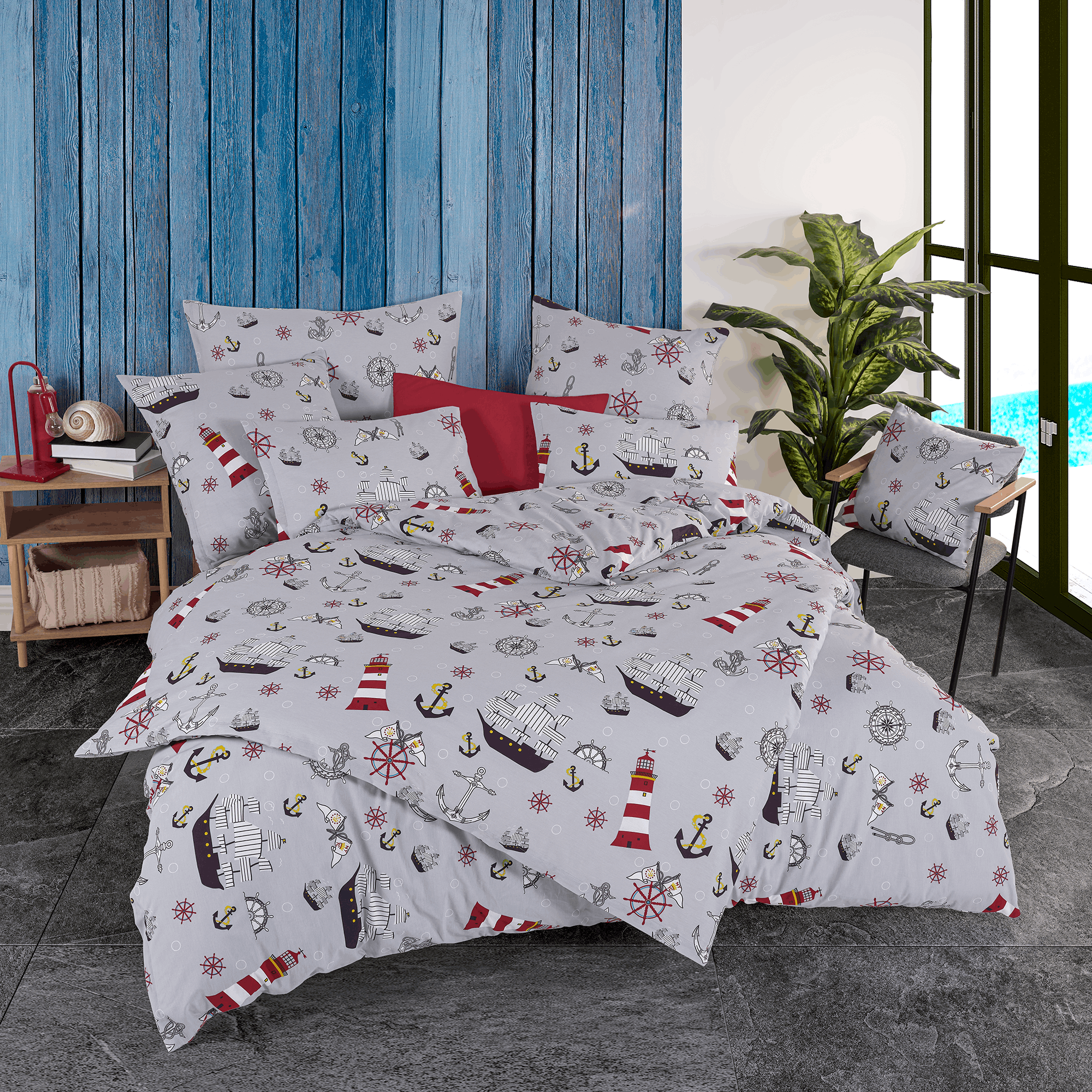 Maritime Bettwäsche komplett aufgezogen auf einem großen Bett vor einer blauen Wand in Holzoptik; das graue Design ist dicht mit roten Leuchttürmen, Segelschiffen und Ankern gemustert.