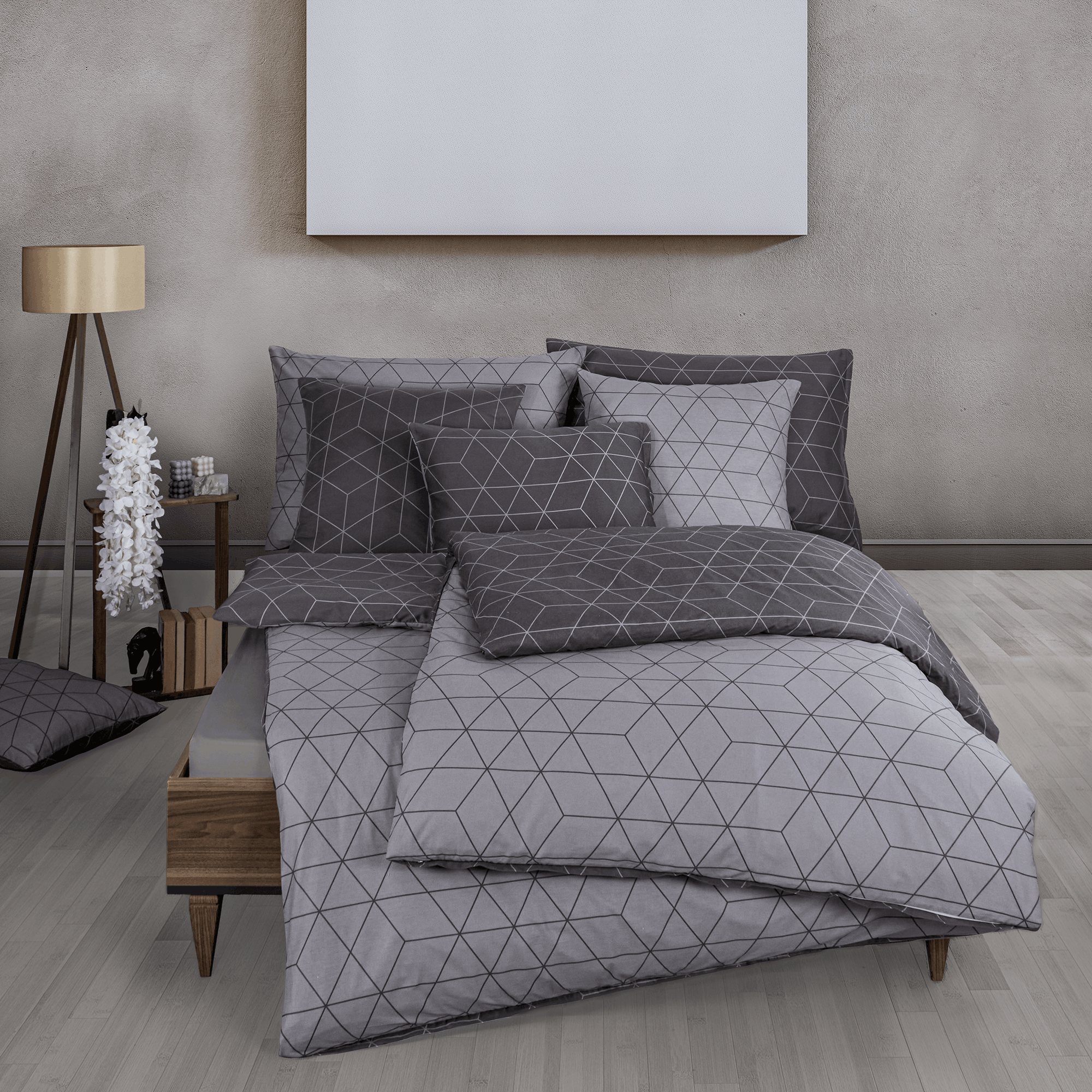 Bett mit grauer Bettwäsche im geometrischen Linienmuster. Modernes Zimmer mit hellem Holzfußboden, Nachttisch, Lampe und passendem Deko‑Kissen.