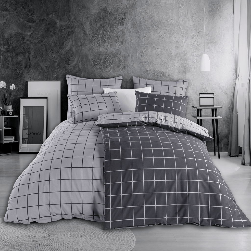 Bett mit grauer Karo‑Bettwäsche in modernem Linienraster. Zimmer mit grauer Wand, Nachttisch, Lampe und minimalistischer Deko.