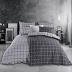 Bett mit grauer Karo‑Bettwäsche in modernem Linienraster. Zimmer mit grauer Wand, Nachttisch, Lampe und minimalistischer Deko.