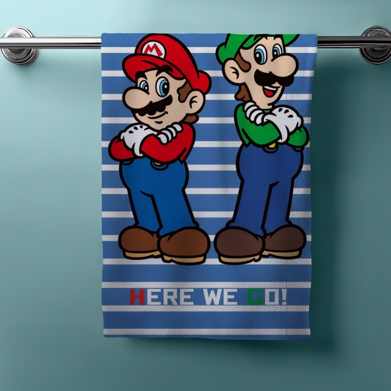 Hängendes Handtuch mit Mario und Luigi, blau‑weiße Streifen, unten „HERE WE GO!“. Hintergrund in Türkis.