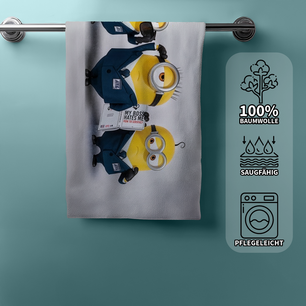 Hängendes Minions‑Handtuch mit drei Minions im Anzug. Einer hält ein Schild. Rechts Icons: 100% Baumwolle, saugfähig, pflegeleicht.