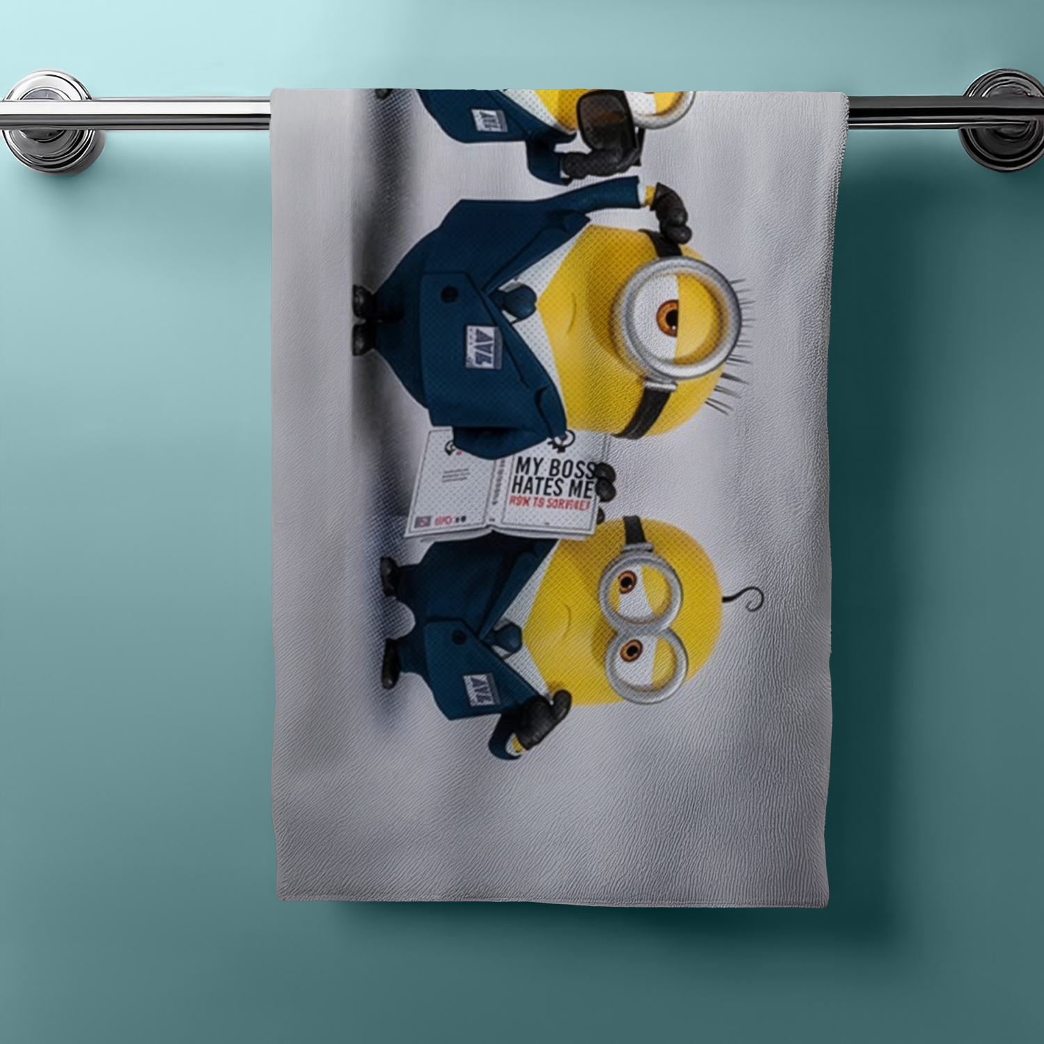 Hängendes Handtuch mit drei Minions im blauen Anzug. Einer hält ein Schild mit Spruch. Hintergrund hellblau.
