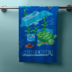 Hängendes blaues Handtuch mit Minecraft‑Unterwassermotiven: Delfin, Schildkröte, Fische, Seegras und Pixel‑Design. Unten Minecraft‑Logo.