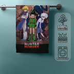 Hunter x Hunter Badetuch an einer Handtuchstange; auf der rechten Seite zeigen drei Icons die Eigenschaften „100% Baumwolle“, „Saugfähig“ und „Pflegeleicht“.