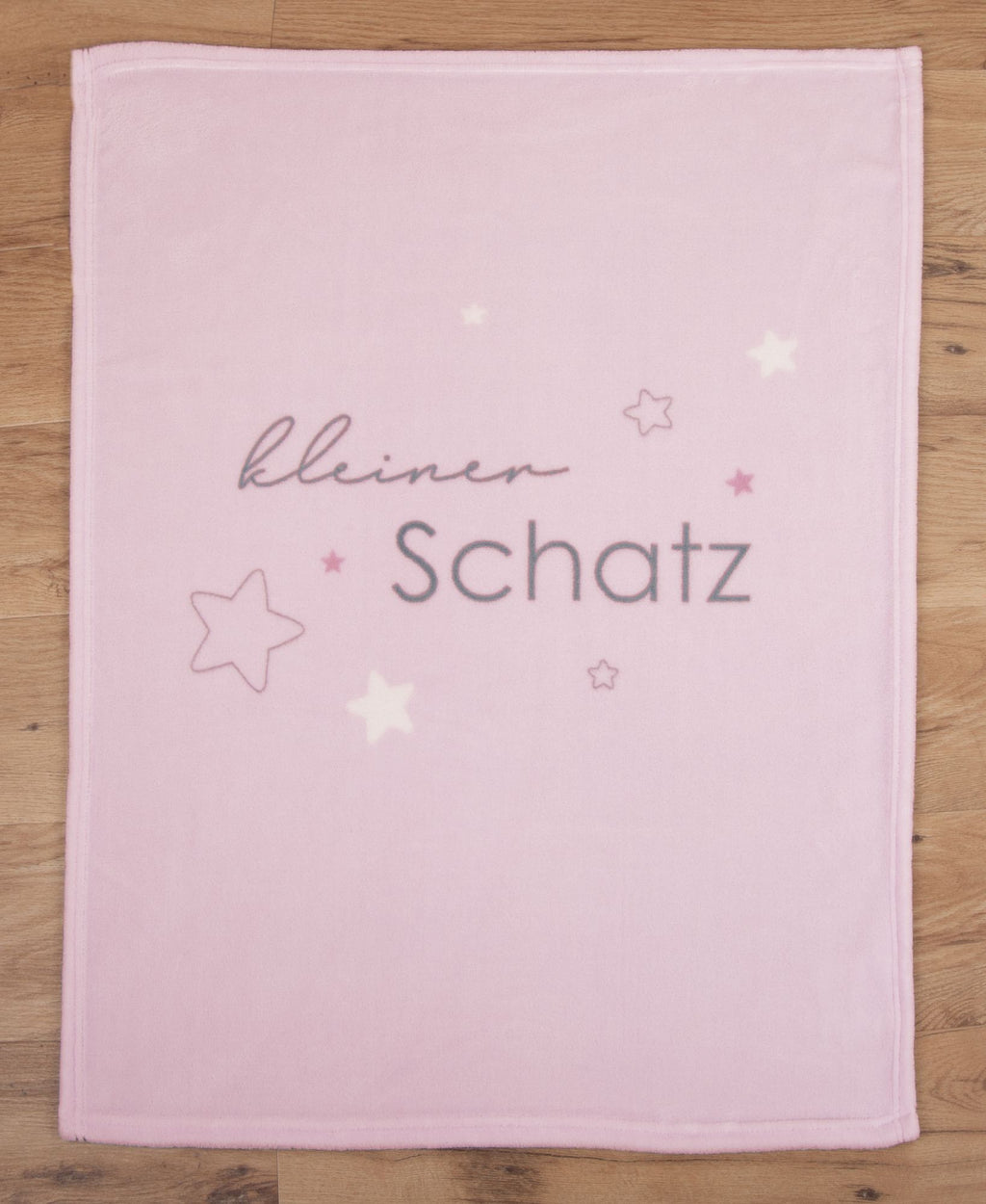 Glatt und gerade ausgebreitete rosa Babydecke in der direkten Draufsicht auf Holzboden.