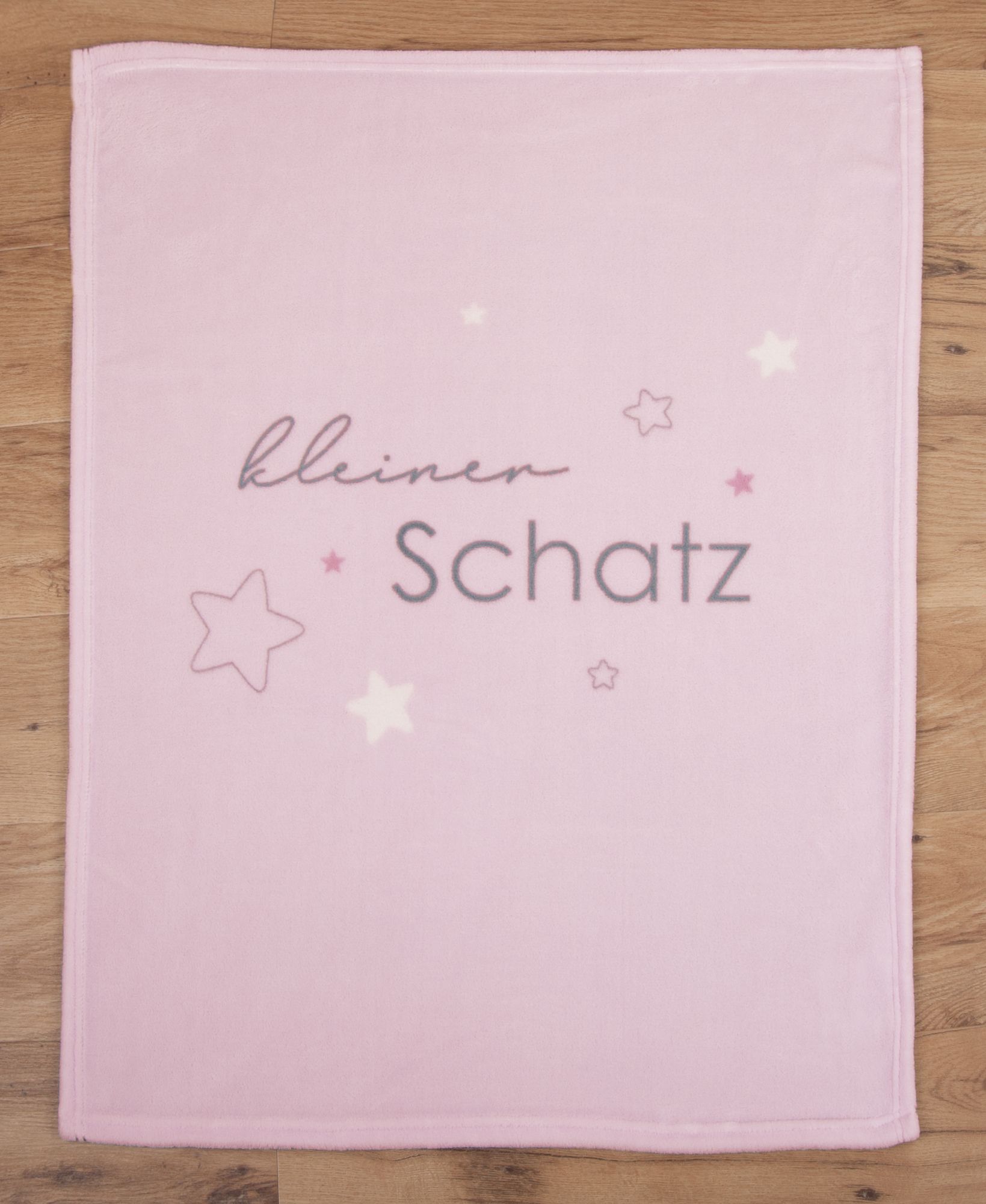 Glatt und gerade ausgebreitete rosa Babydecke in der direkten Draufsicht auf Holzboden.