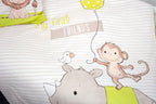 Nahaufnahme der Babybettwäsche; im Fokus stehen ein gezeichnetes Nashorn mit einem kleinen Vogel auf dem Kopf sowie ein Äffchen, das einen gelben Luftballon hält, vor einem gestreiften Hintergrund mit dem Schriftzug „My first FRIENDS“.