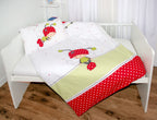 Ambiente-Aufnahme der Babybettwäsche in einem weißen Gitterbett; die Decke zeigt den sitzenden Käfer-Charakter über einem grün-weiß karierten Balken und einem rot-weiß gepunkteten Abschluss.