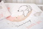 Nahaufnahme der Babybettwäsche im weißen Gitterbett, die das Motiv des kleinen Hasen auf dem schlafenden Mond sowie den liebevollen Schriftzug „Some bunny loves you“ im Detail zeigt.