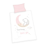 Produktansicht der Babybettwäsche freigestellt auf weißem Hintergrund; zeigt das komplette Set bestehend aus dem rosa-weiß gestreiften Kissen und dem Deckenbezug mit dem zentralen Hasen-Motiv in der direkten Draufsicht.