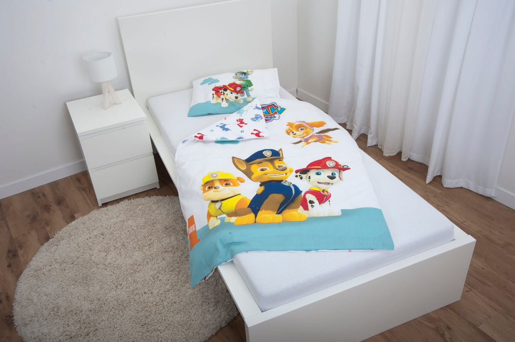 Ambiente-Aufnahme der Kinderbettwäsche in einem weißen Jugendbett; die Decke ist leicht umgeschlagen und lässt das bunte Allover-Muster der Rückseite mit kleinen Fahrzeug-Silhouetten erkennen.