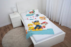 Ambiente-Aufnahme der Kinderbettwäsche in einem weißen Jugendbett; die Decke ist leicht umgeschlagen und lässt das bunte Allover-Muster der Rückseite mit kleinen Fahrzeug-Silhouetten erkennen.