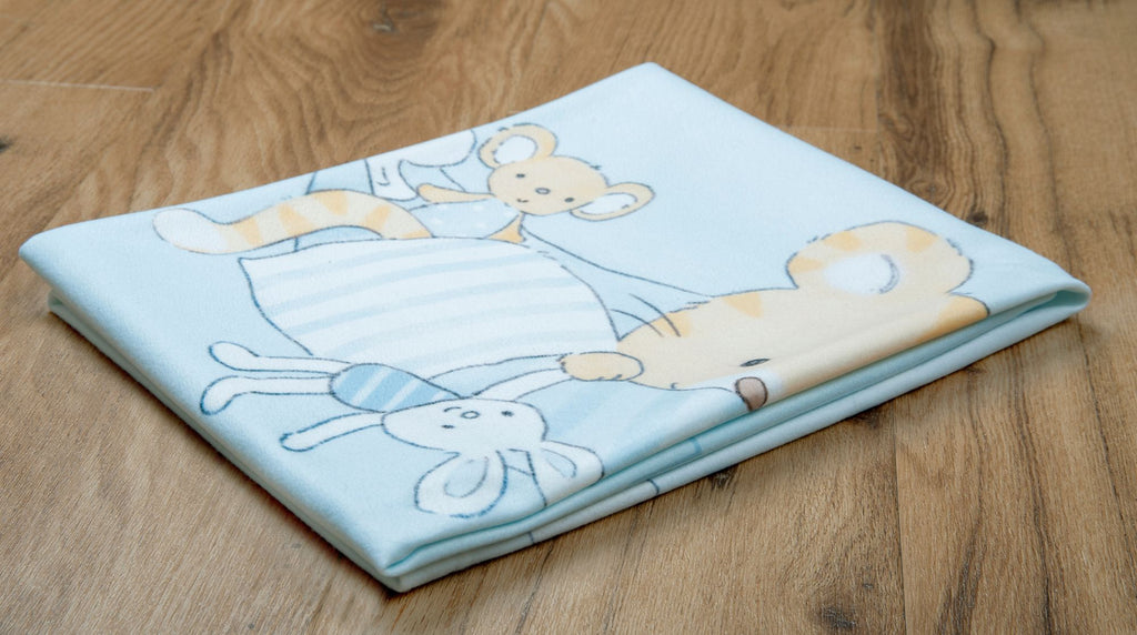 Perspektivische Ambiente-Aufnahme der hellblauen Babydecke, die zusammengelegt auf einem hellen Holzboden liegt; zeigt das gedruckte Motiv mit dem kleinen Tiger, einer Maus und einem Kuschelhasen.