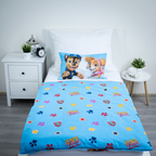 Ambiente-Aufnahme des komplett bezogenen Kinderbettes; präsentiert die hellblaue Wendeseite des Bettbezugs mit dem Allover-Muster aus Sternen, Pfoten und dem „ONE Team“-Schriftzug.