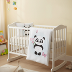 Ambiente-Aufnahme der Babybettwäsche im Kinderzimmer; zeigt das Panda-Motiv auf der Decke, die dekorativ über das vordere Gitter des weißen Babybettes gehängt ist.