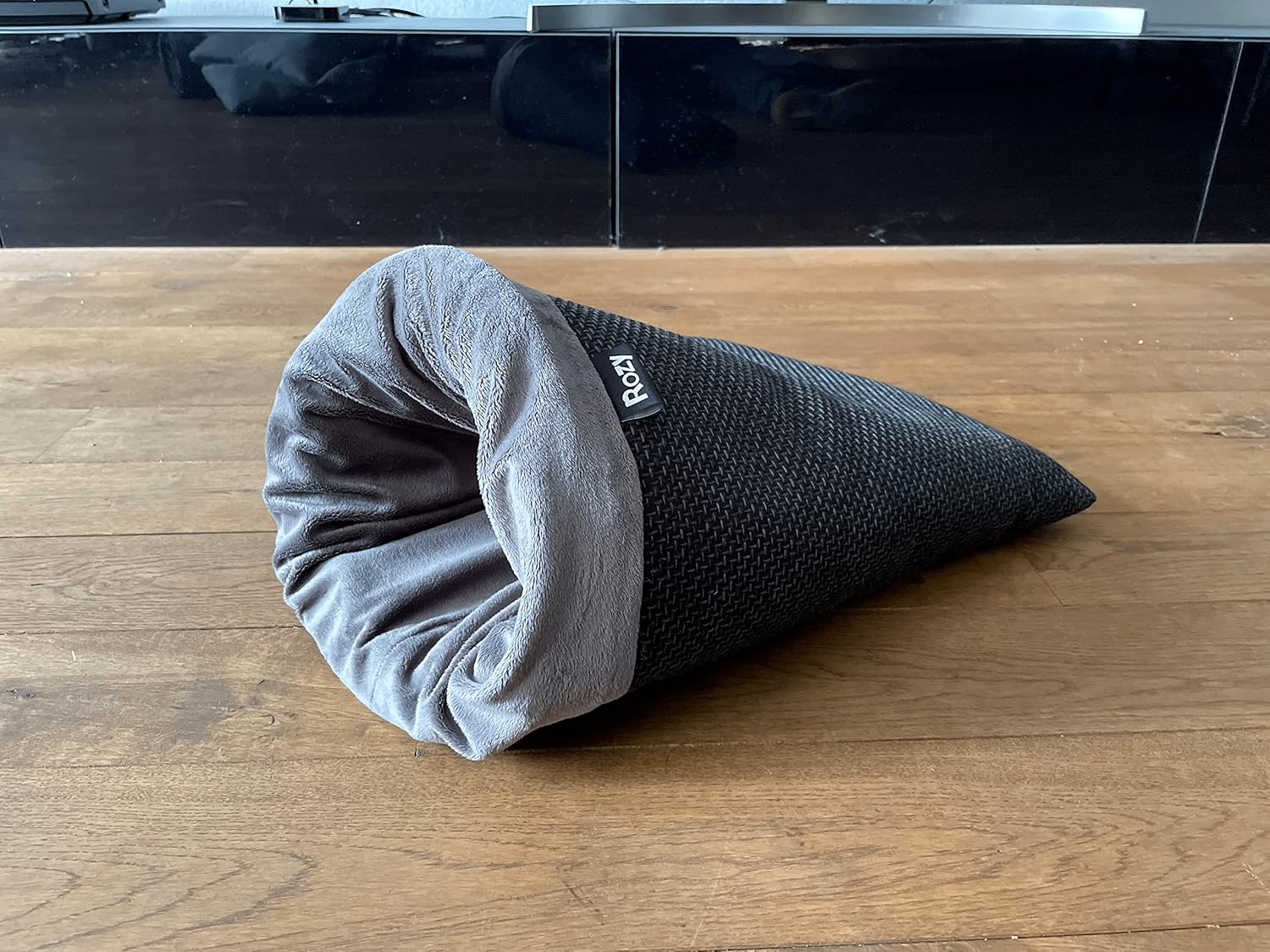 Dunkelgrauer, kegelförmiger Kleintier-Kuschelsack Rozy mit weichem Plüschfutter, fotografiert auf hellem Holzfußboden.