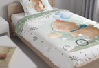 Detailansicht der aufgezogenen Kinderbettwäsche auf einem Holzbett mit dem Motiv eines fahrradfahrenden Bären und Vögelchen.
