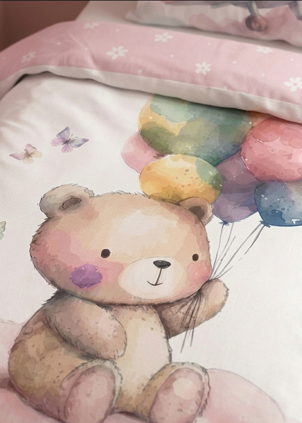 Nahaufnahme der Bettdecke mit Aquarell-Motiv eines niedlichen Bären, der bunte Luftballons hält, und rosafarbenem Umschlag.