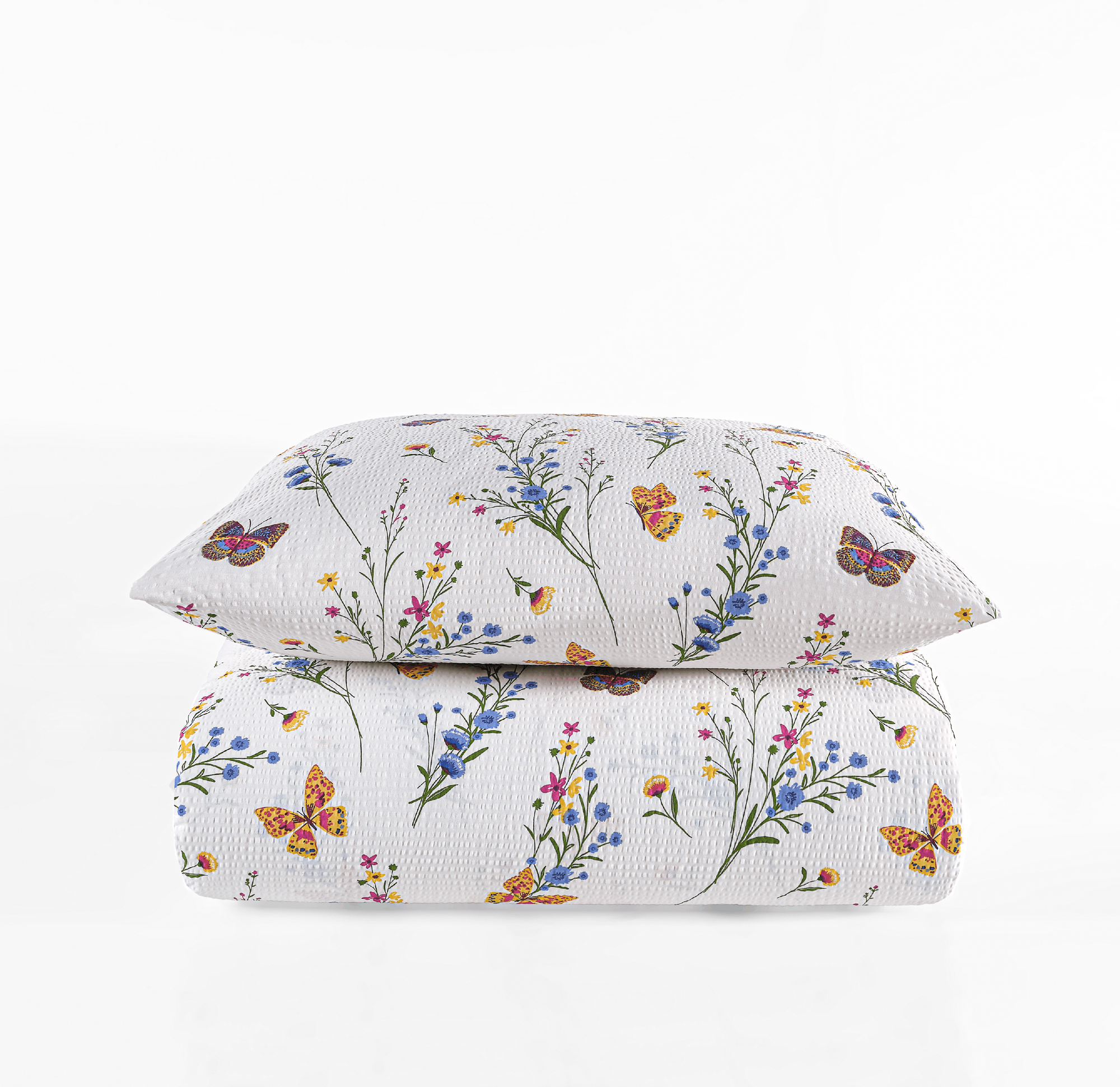 Zusammengefaltete weiße Seersucker-Bettwäsche mit Kopfkissen, bedruckt mit bunten Wiesenblumen und Schmetterlingen.