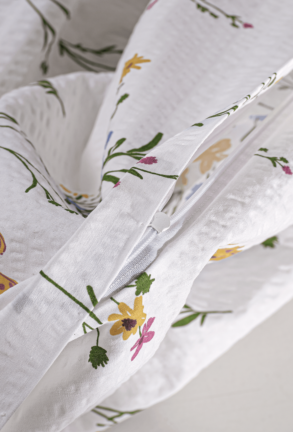 Detailaufnahme des verdeckt eingenähten Reißverschlusses an der weiß-beigen Seersucker-Bettwäsche mit Blumenprint.