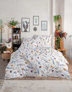 Bettwäsche-Set mit Blumen- und Schmetterlingsmotiv auf einem Doppelbett in moderner Raumkulisse mit Zimmerpflanzen.