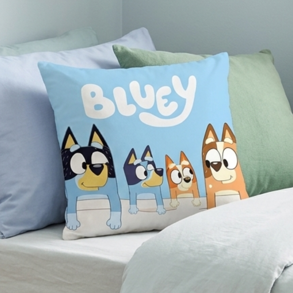 Nahaufnahme der blauen Vorderseite des Bluey-Kissens mit der ganzen Familie Heeler auf einem Bett.