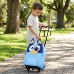 Kind zieht den blauen Bluey Trolley-Rucksack auf einem gepflasterten Weg im Park.